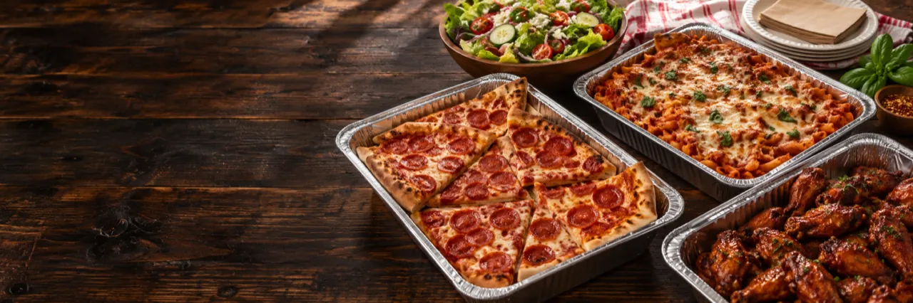 Catering trays of pepperoni pizza, baked ziti, wings and salad