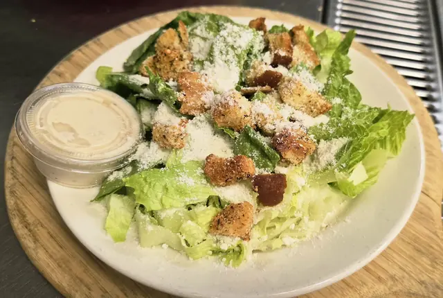 Caesar salad with croutons and dressing on the side