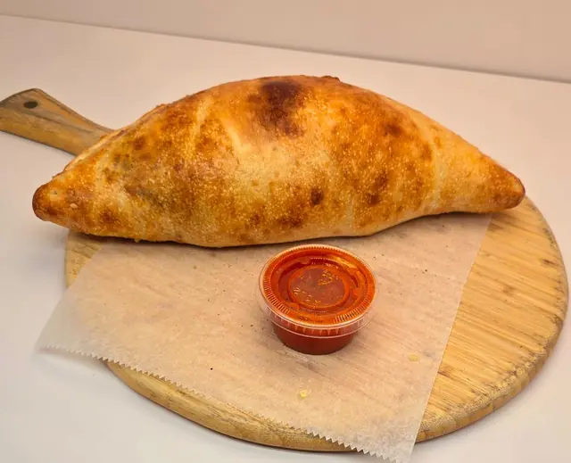 Golden baked calzone with marinara for dipping